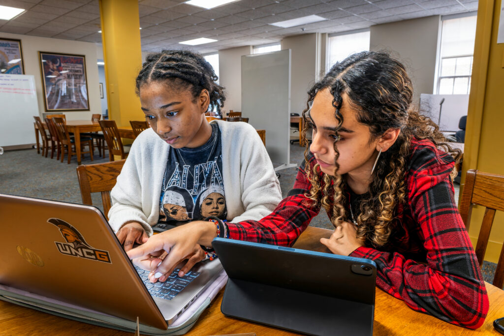 A photo of two students typing on laptop computers in Jackson Library.