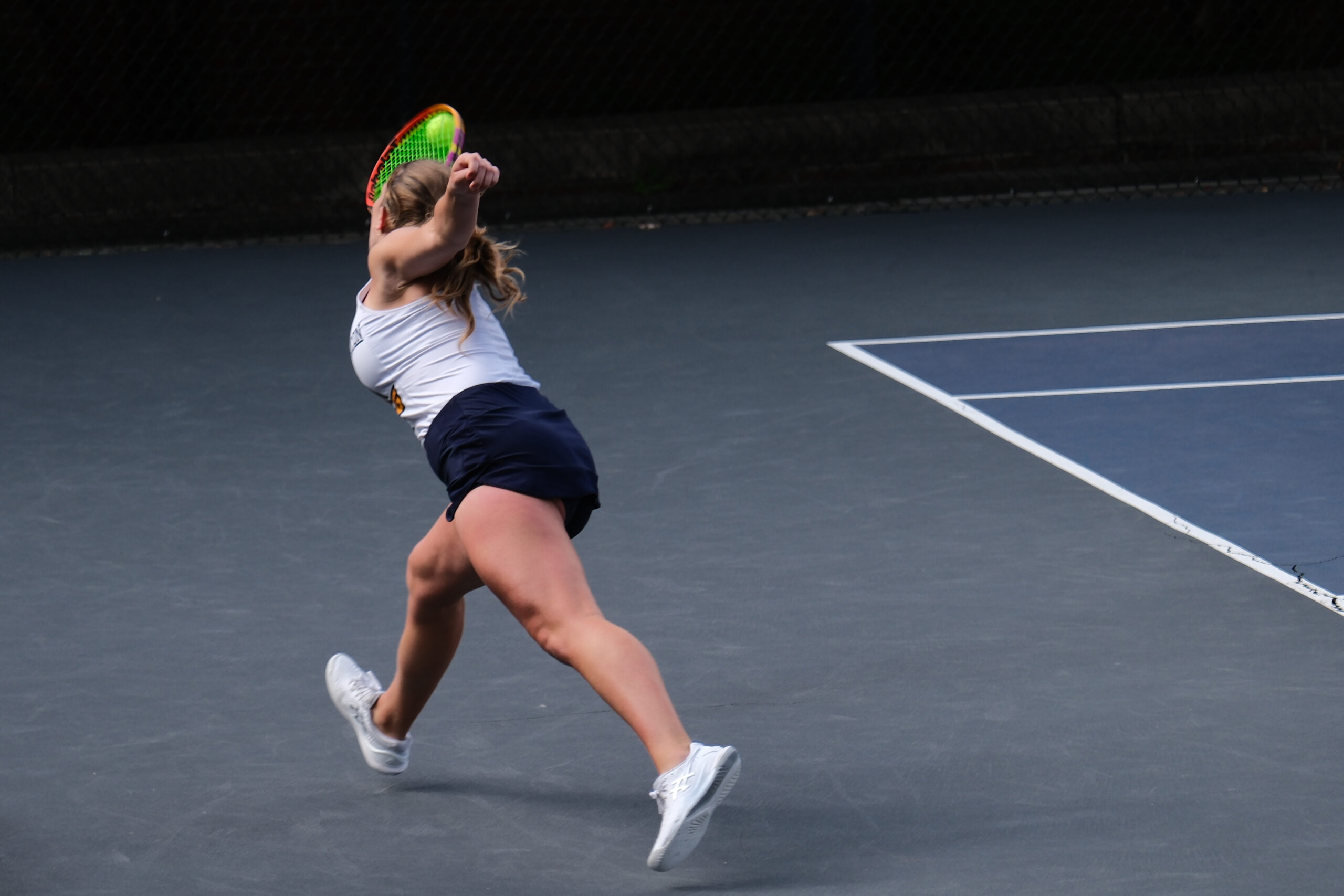 Tennis player stretches to make a shot.