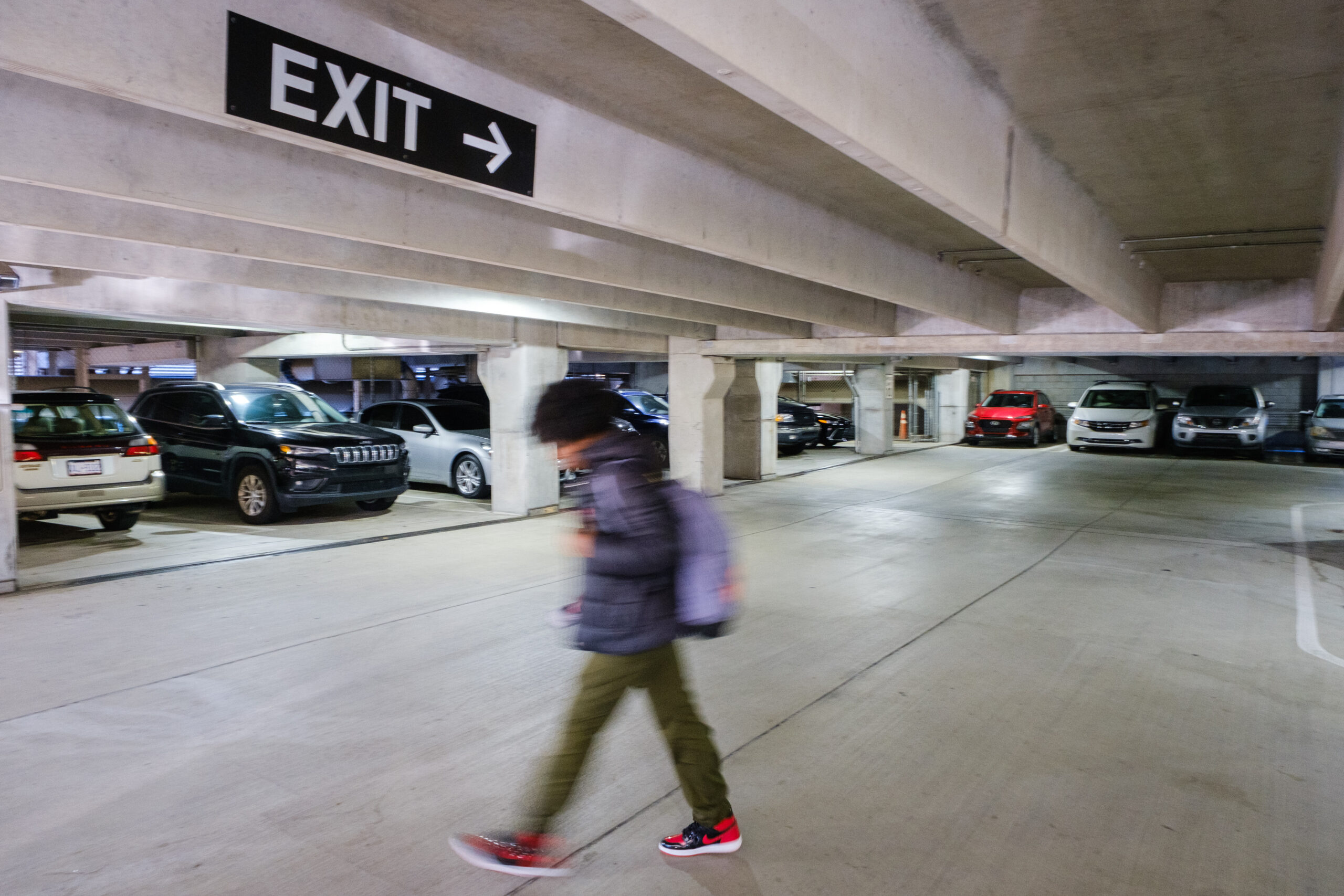 A student dressed for winter strides across a parking deck