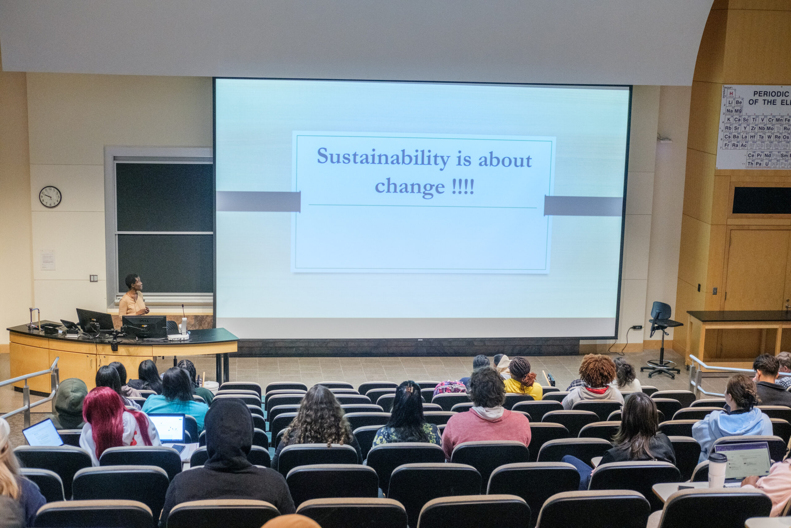 Presentation in a college lecture classroom with a screen at the head of the class.