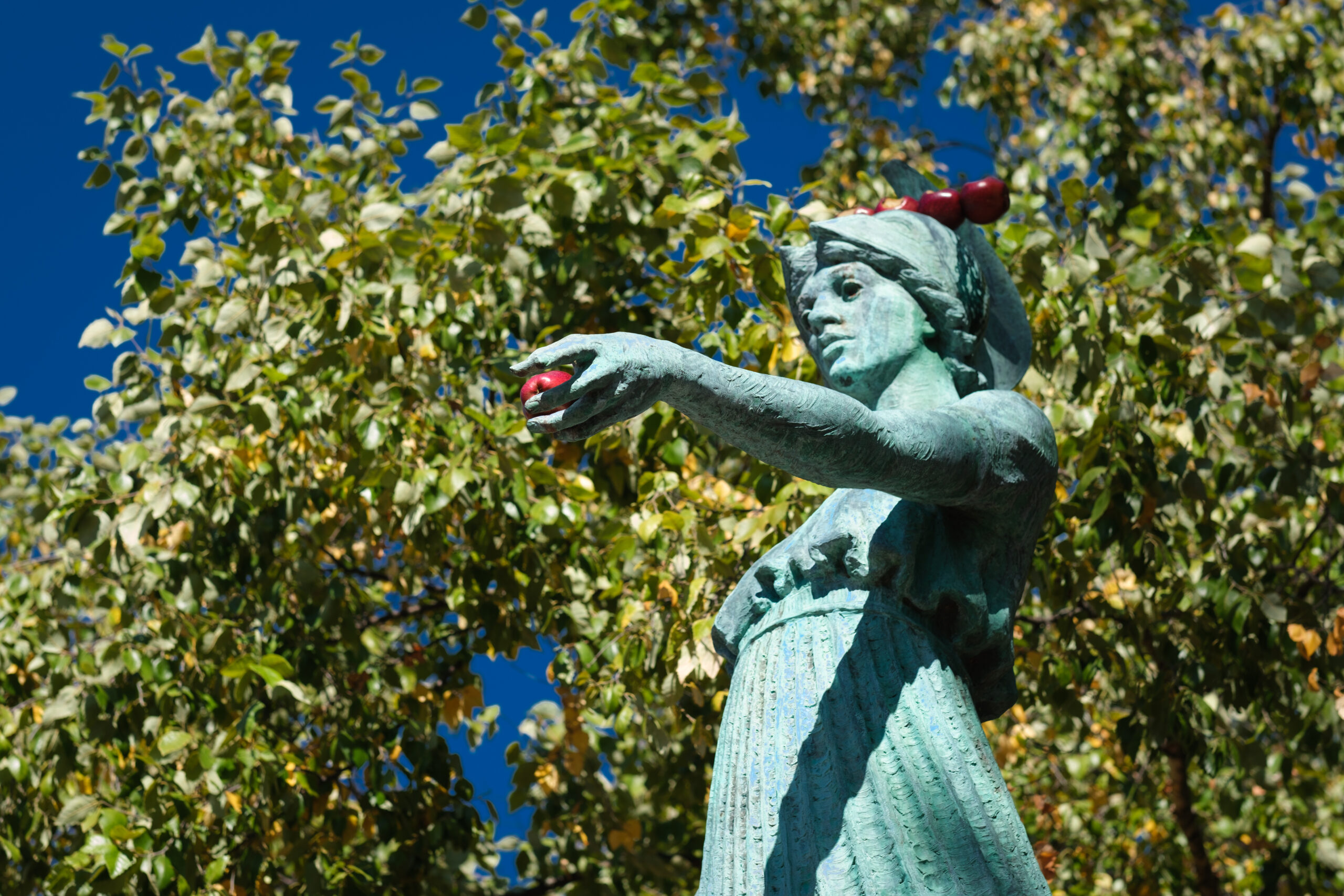 Statue of Minerva, arm outreached with apple in her hand and four apples on her head