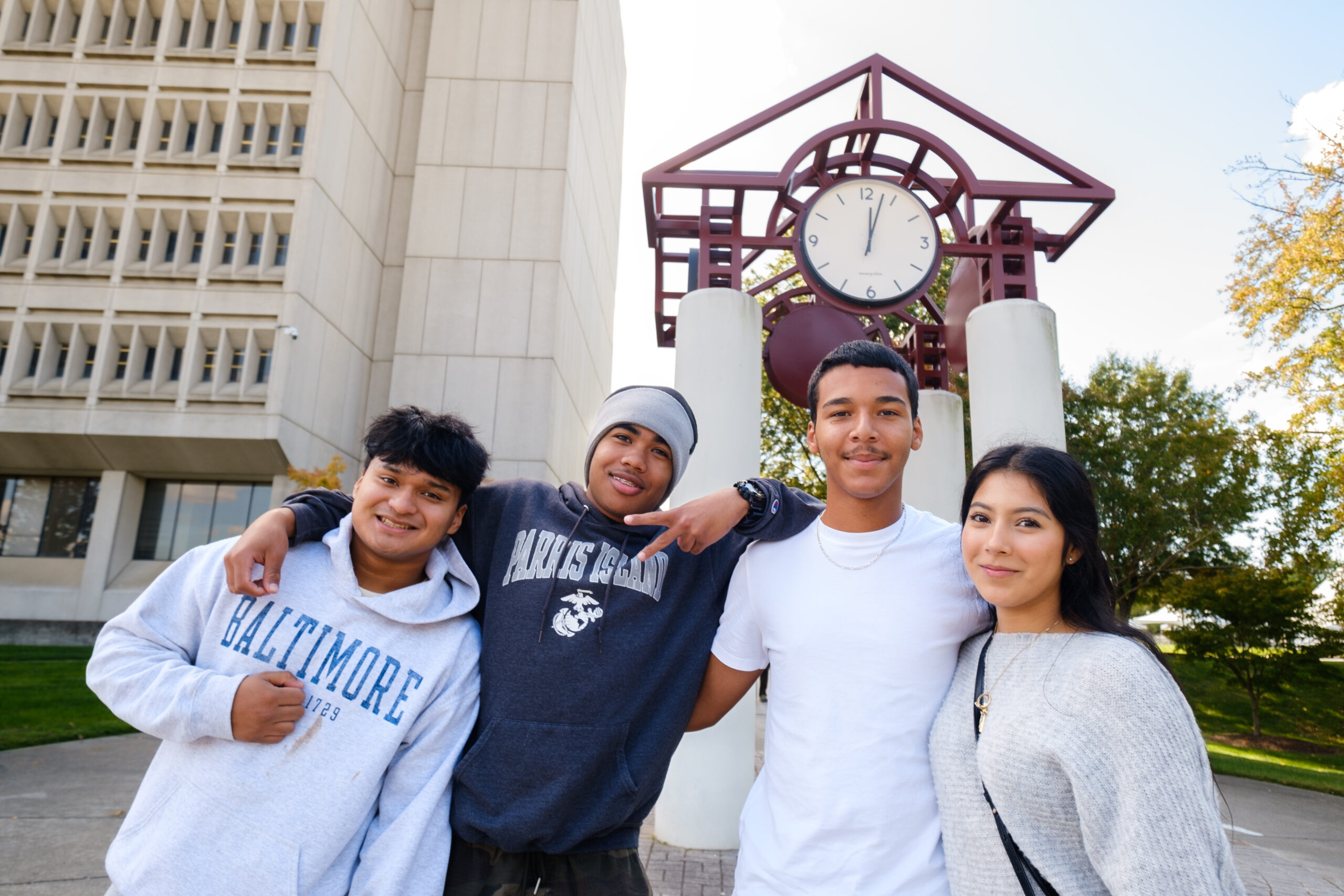 Friends pose together beside the UNCG clock tower.