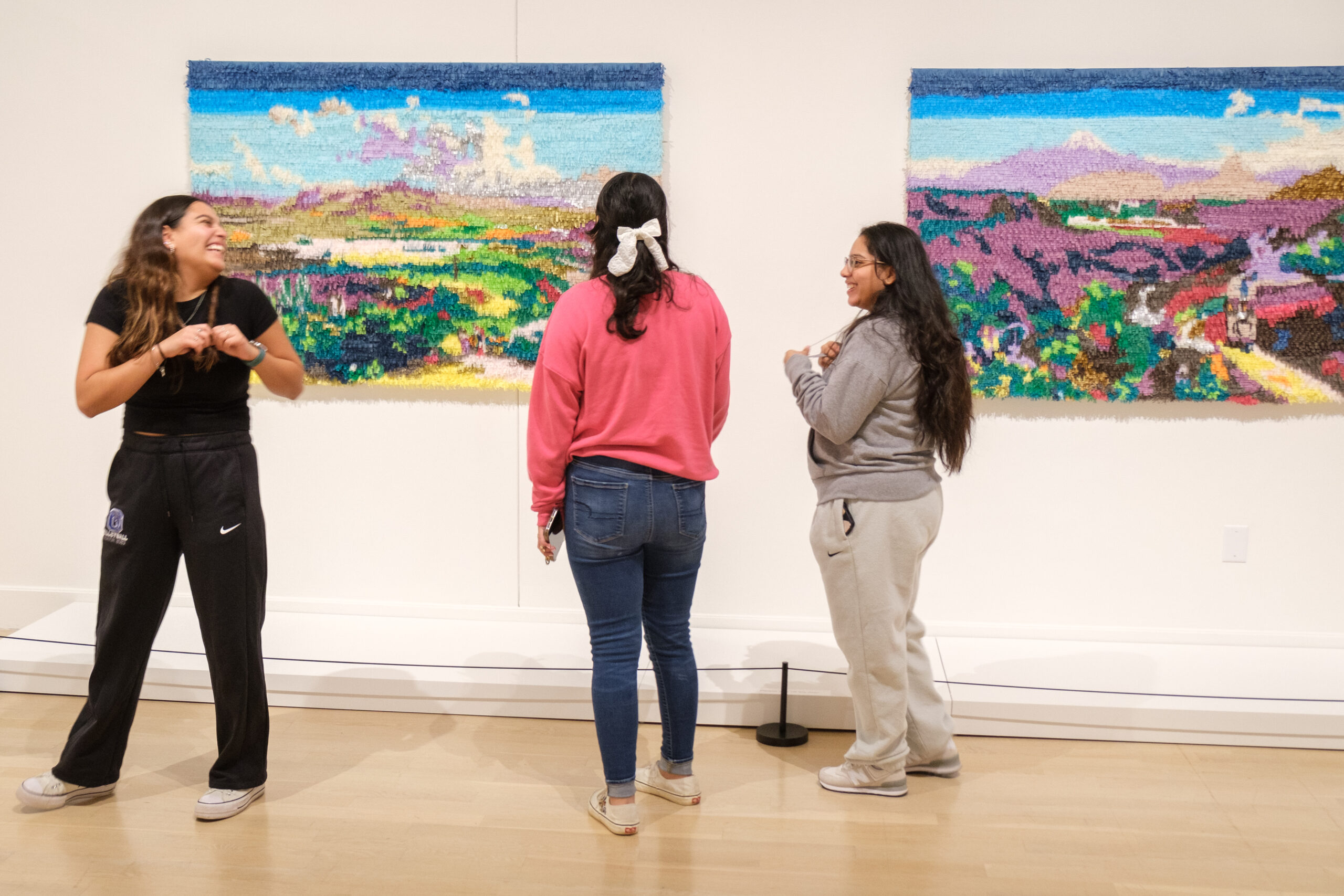 Students stand in front of paintings at UNCG.