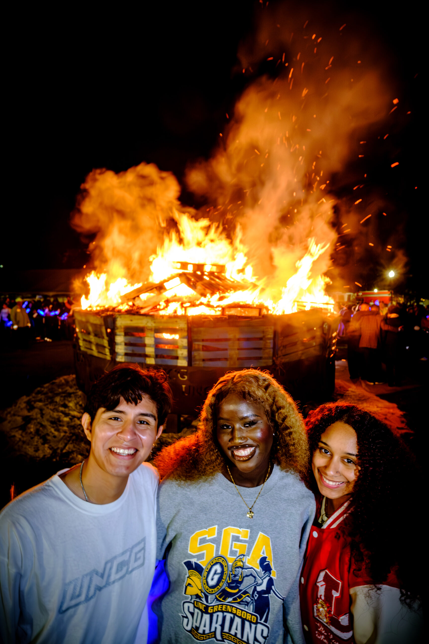 Three students enjoying the Homecoming bonfire