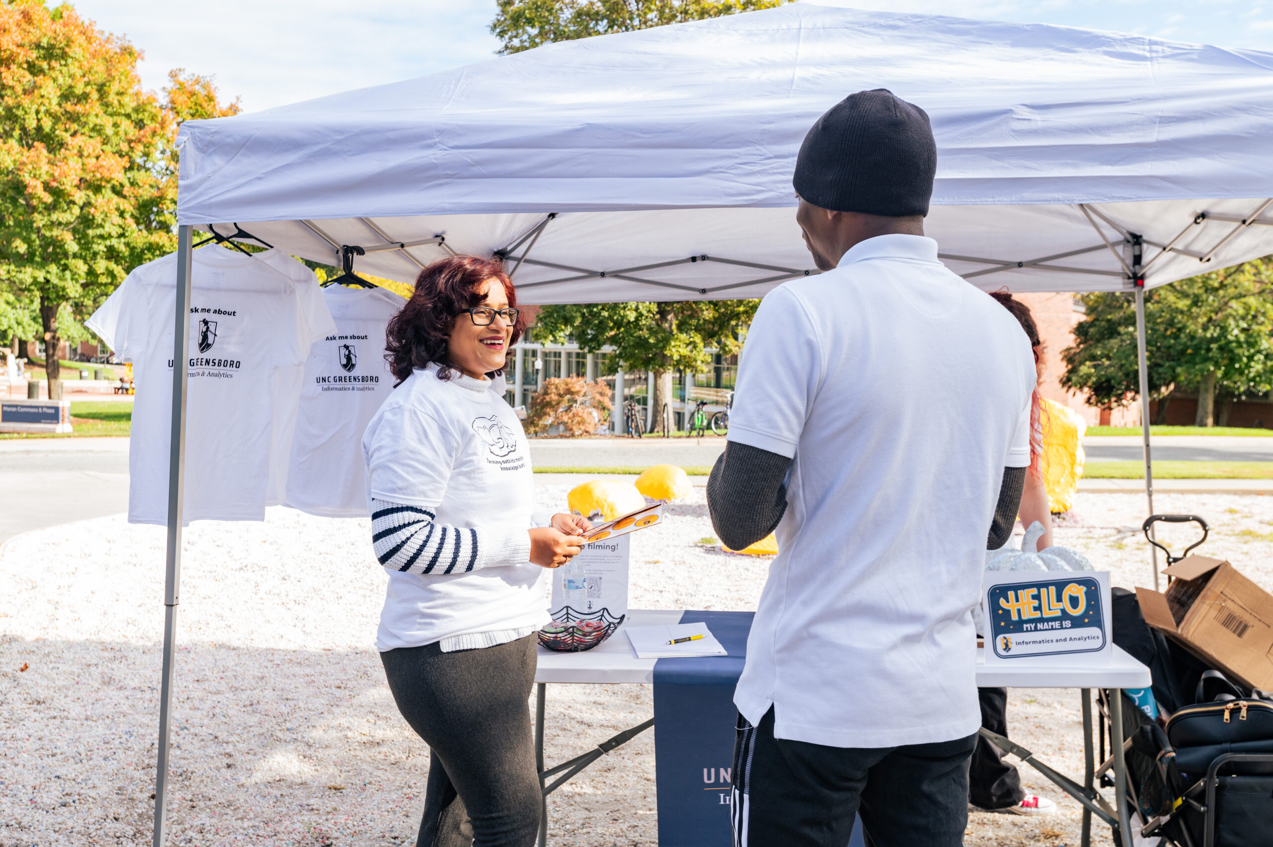 UNCG's Dr. Prashanti Manda talks to a student under a tent.