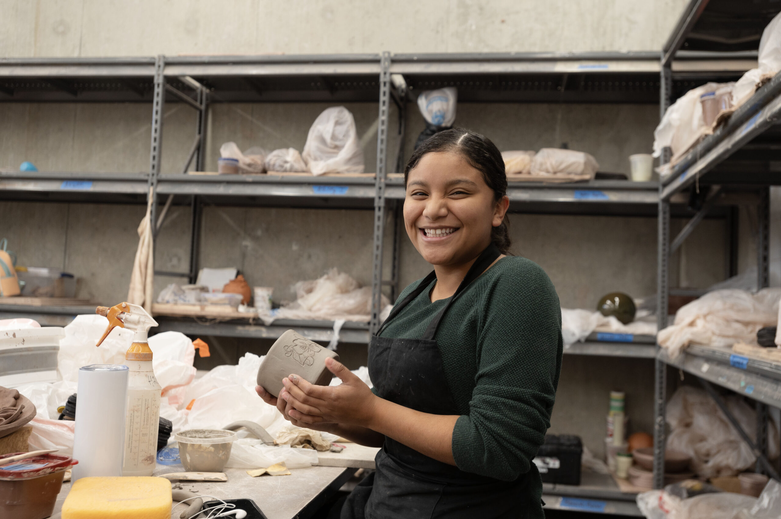 Smiling student works in a ceramics studio.