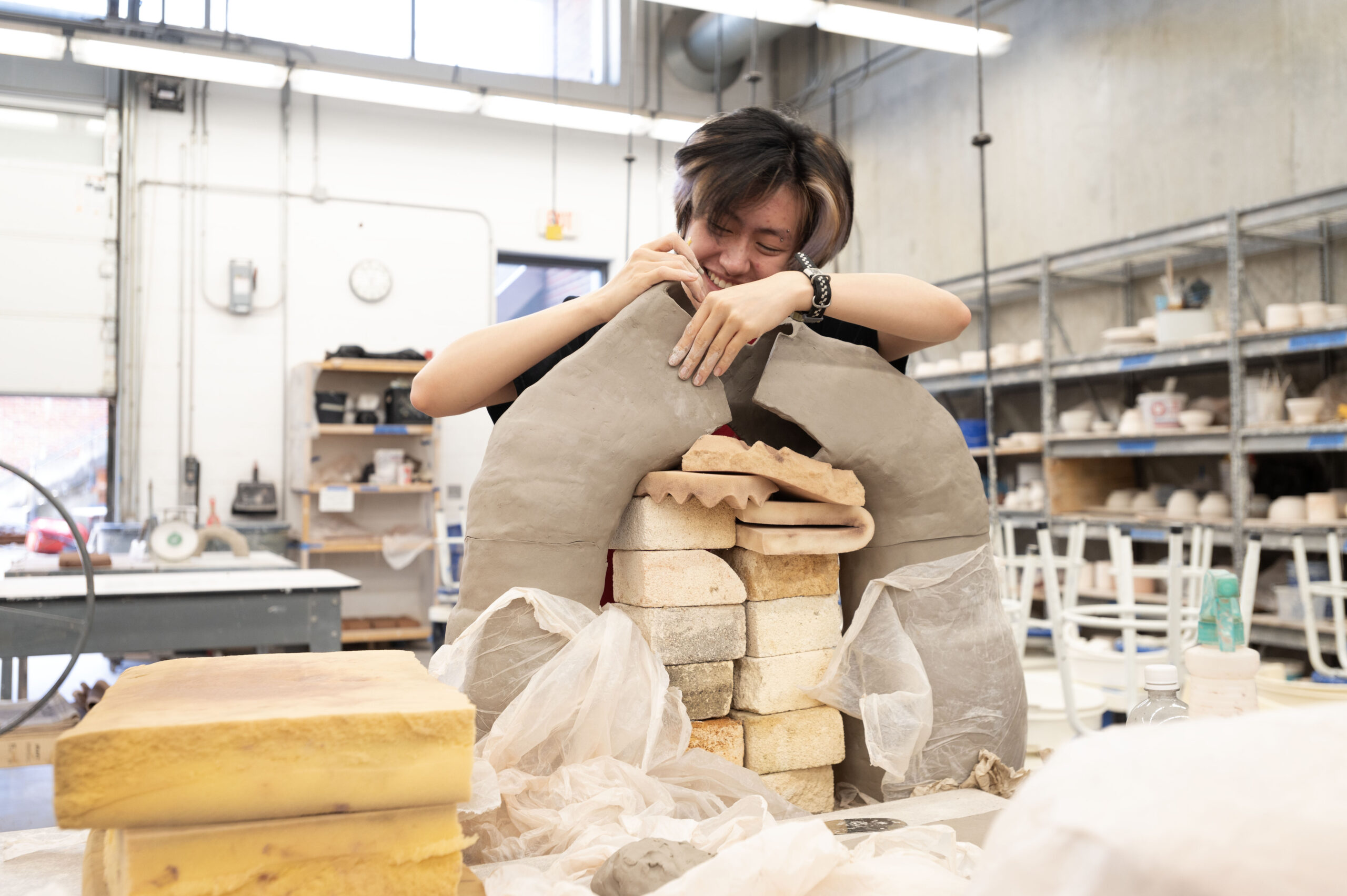Art student works on a sculpture in a studio.