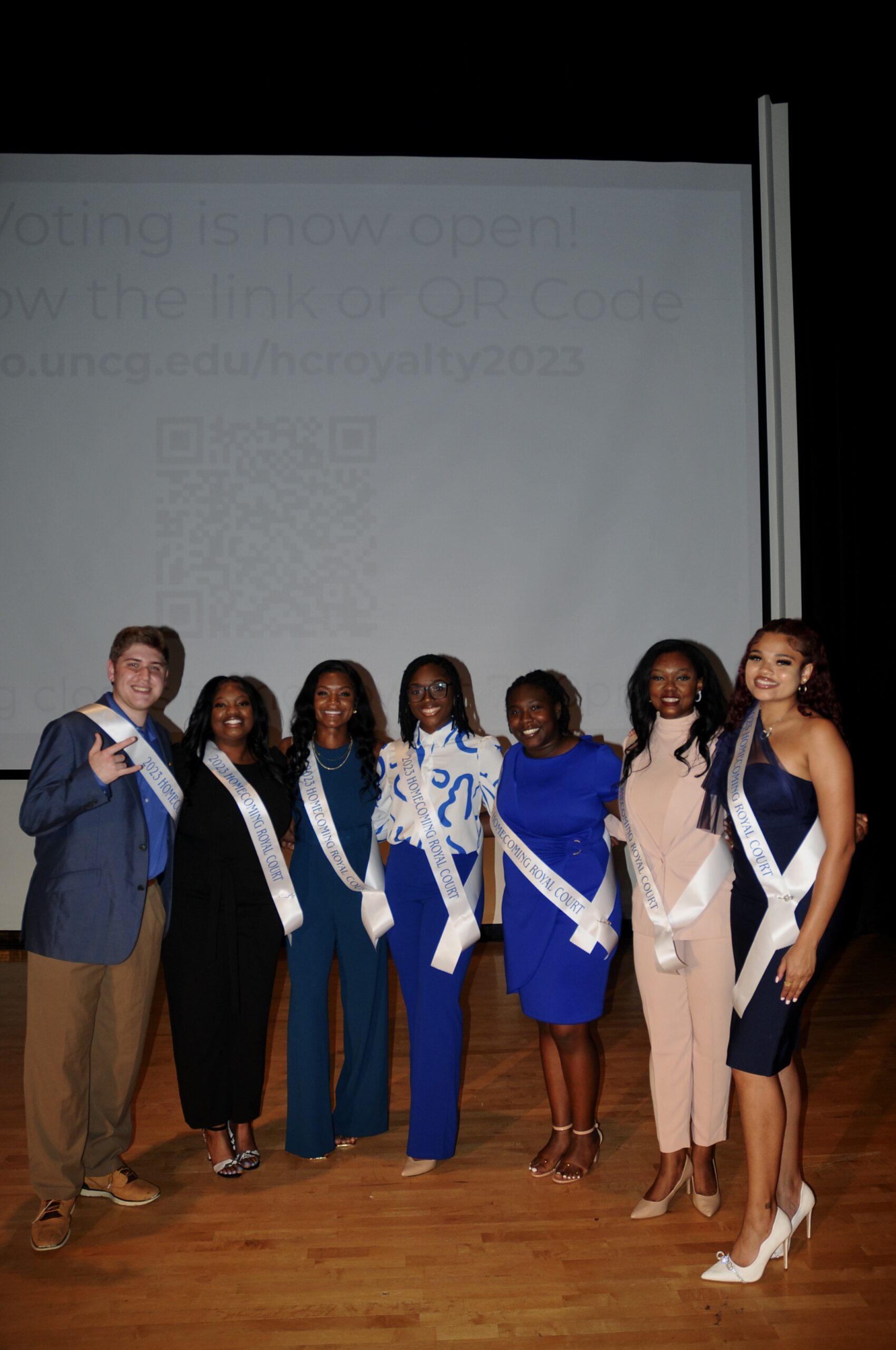 Seven students pose together wearing formal attire and 2023 Homecoming Court sashes.