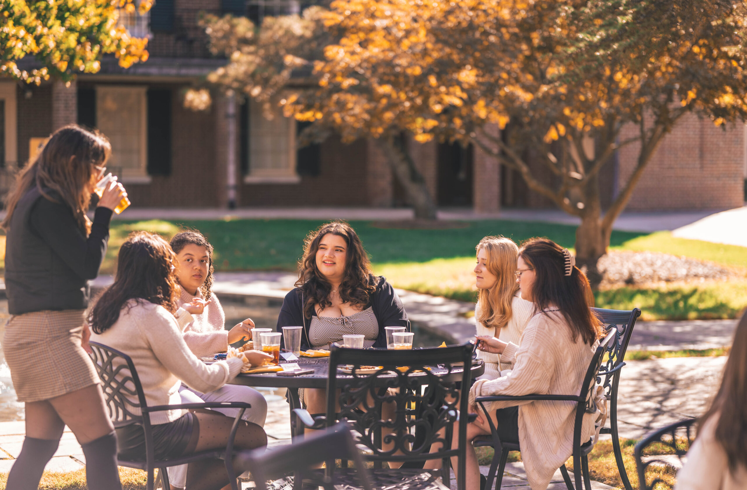 Group of young women eating at an outdoor table on a fall day.