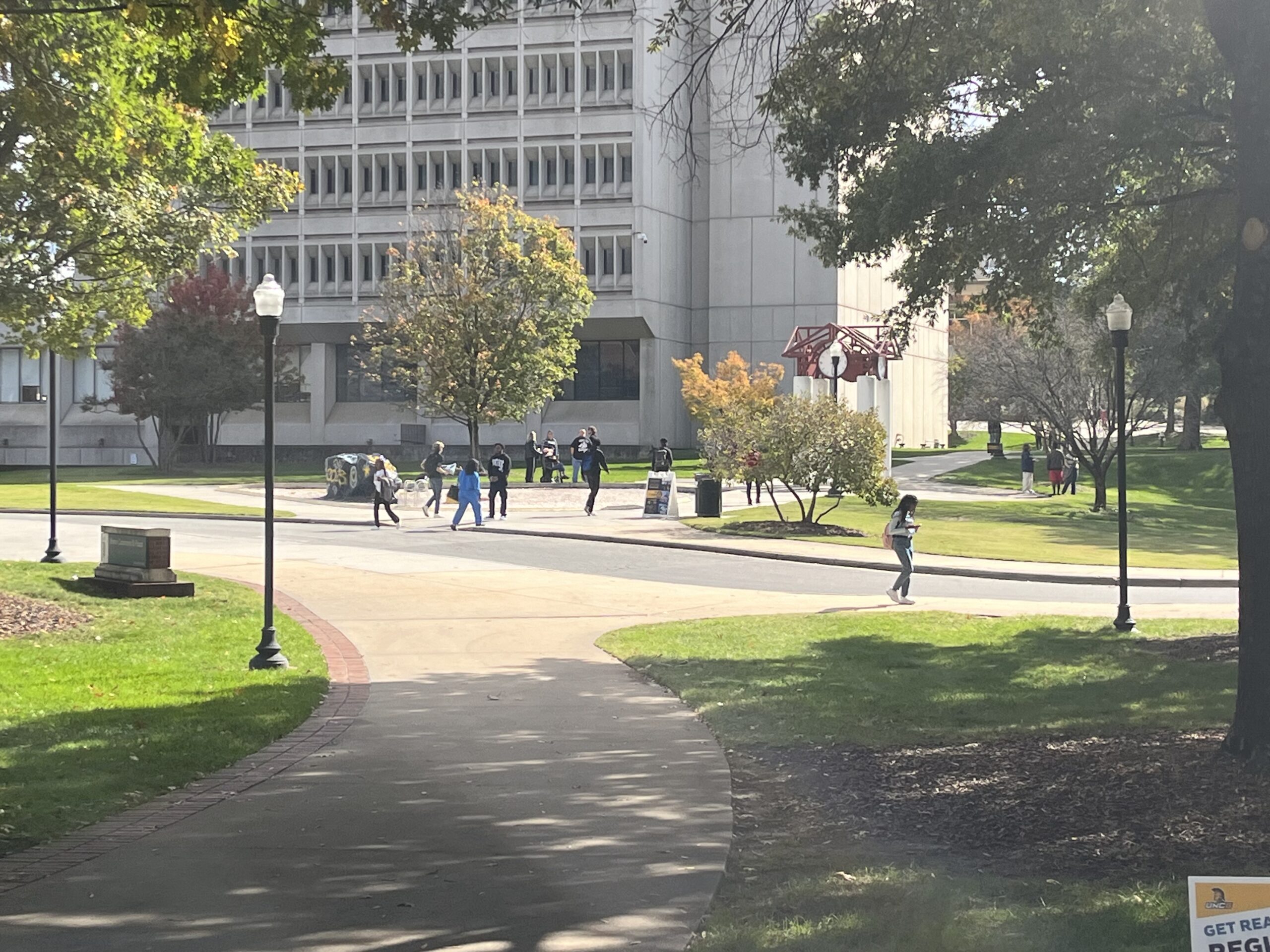 Image, taken from a distance, of students walking in front of the library.