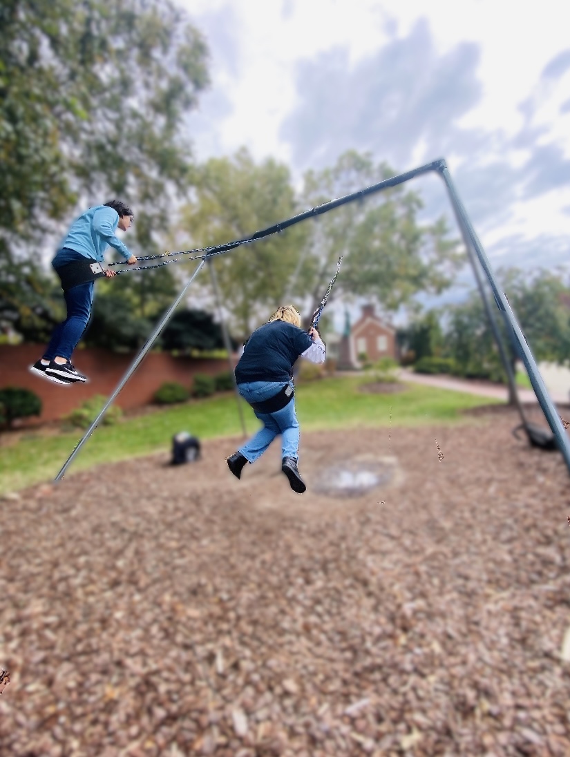 Students swing on a swing set at UNCG