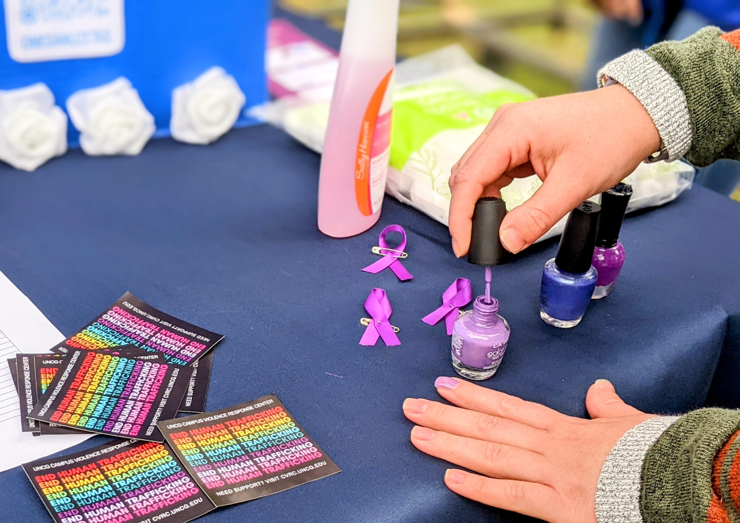 A UNCG student paints fingernails purple.