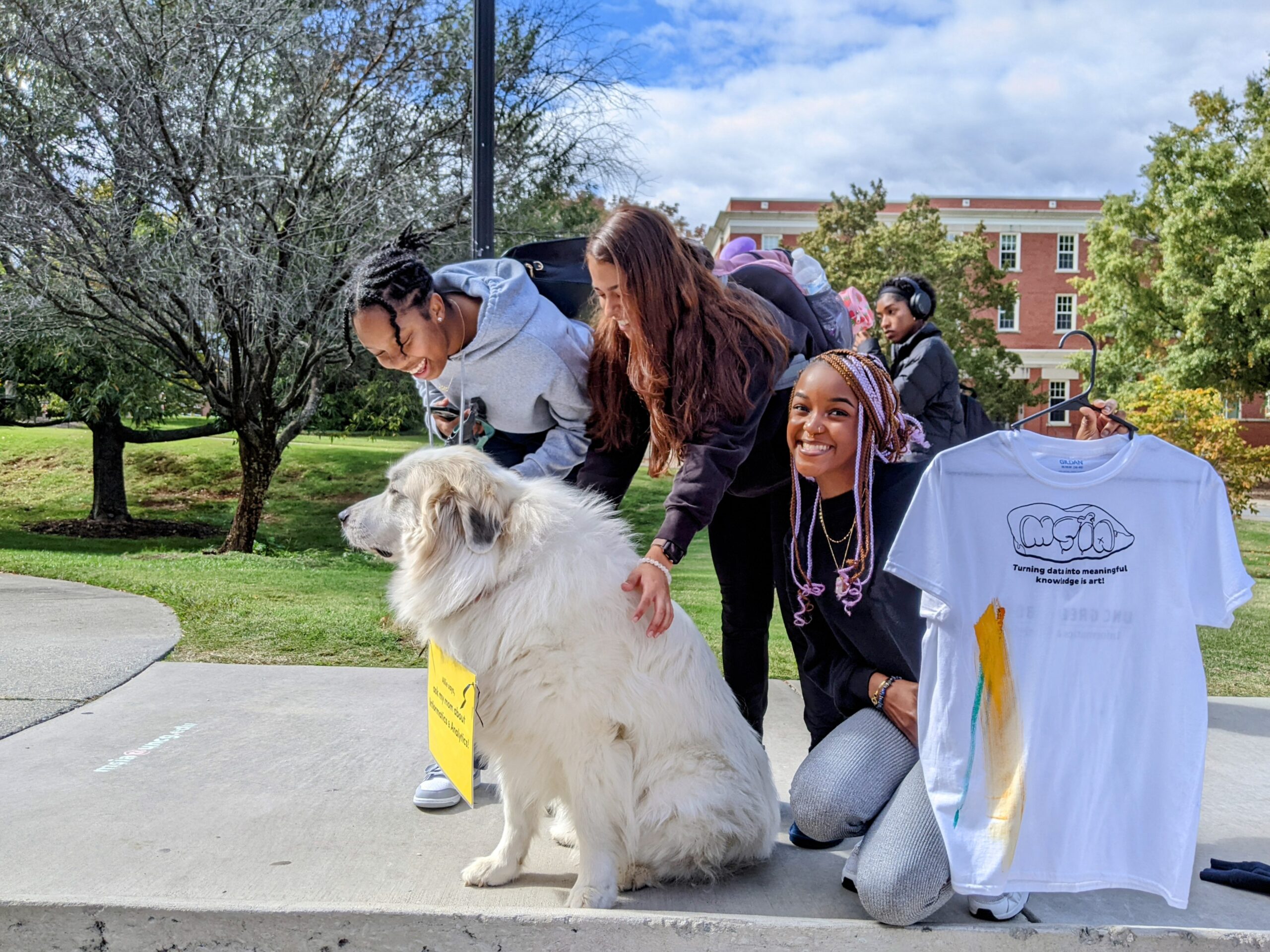 Three UNCG student pet a dog