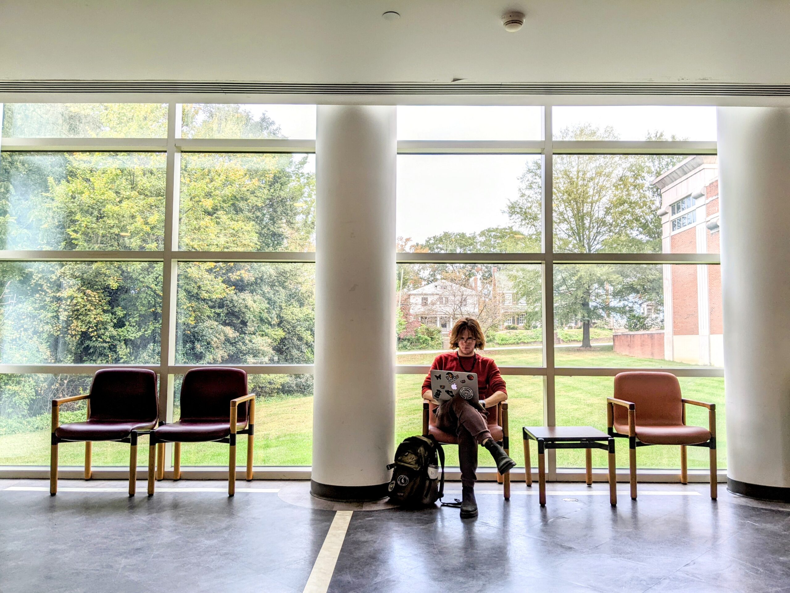 A UNCG student sits in the School of Music lobby with his backpack.