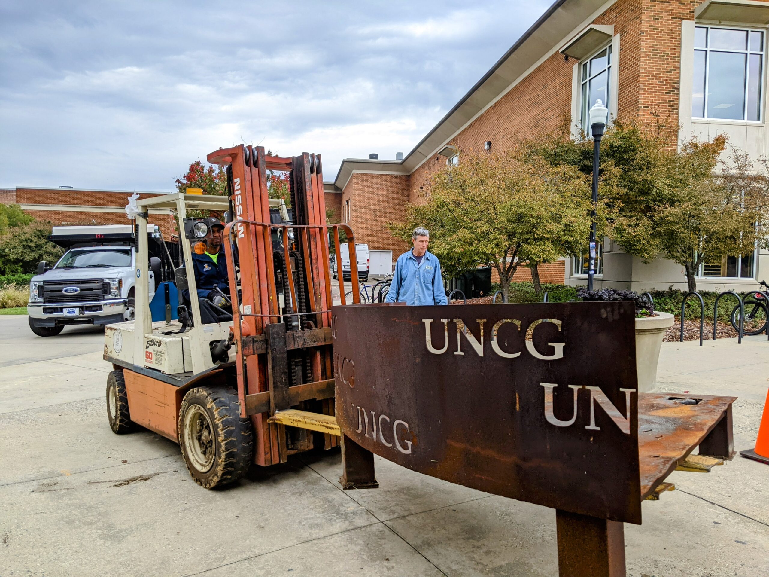 UNCG staff move the metal barrier that will hold the Homecoming bonfire.