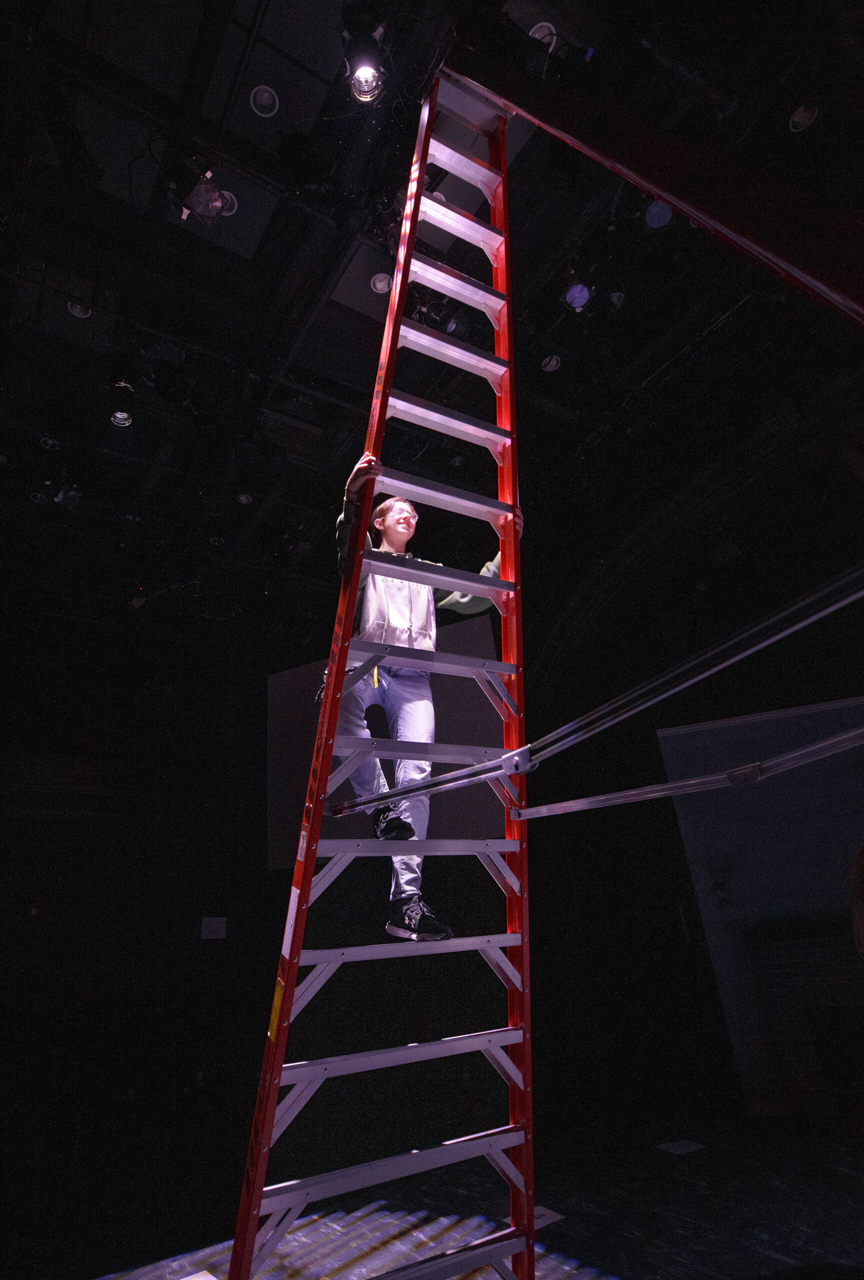 Person climbs a ladder in a dark room.