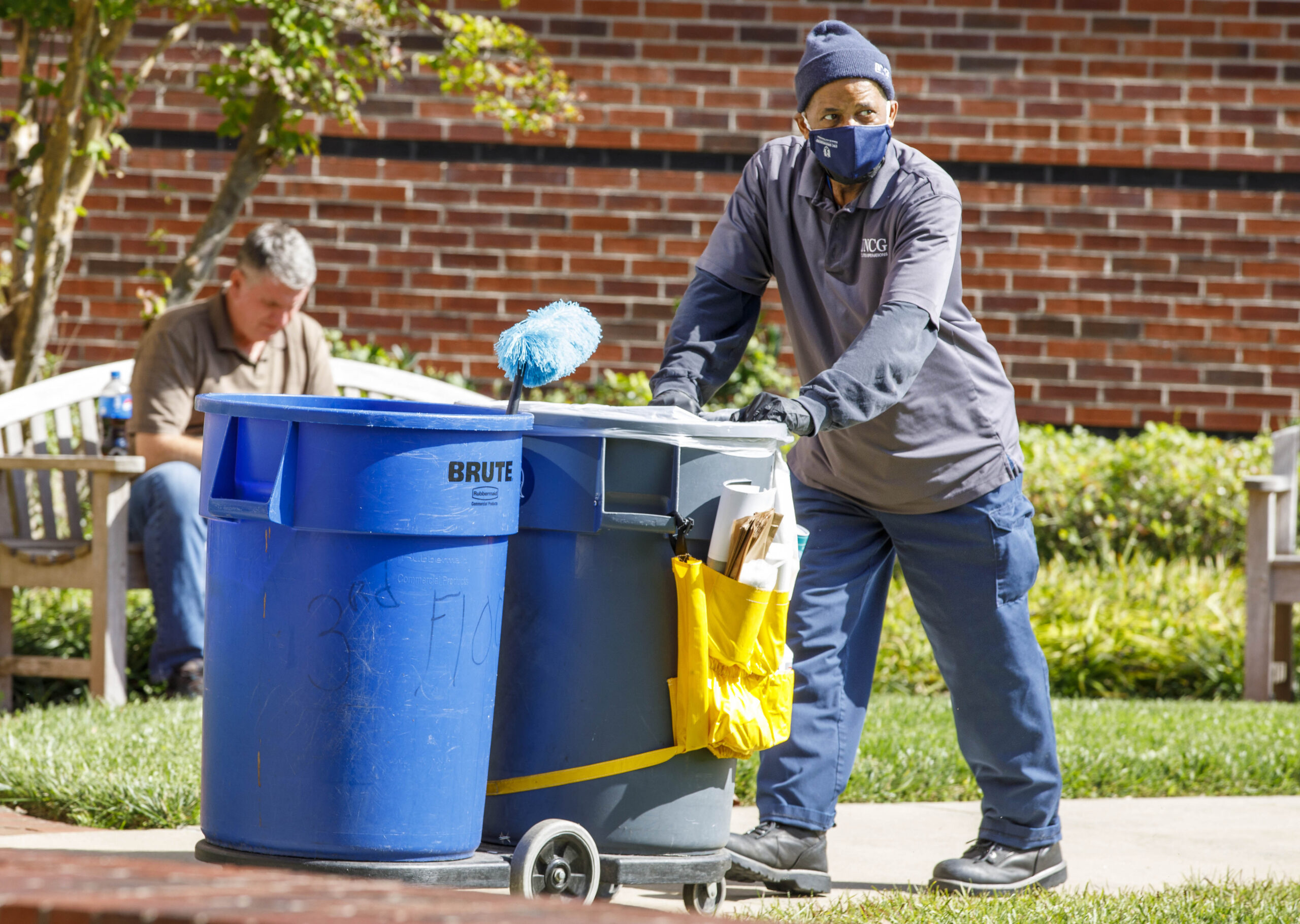 UNCG staffmember Leon Brown moves garbage bins outside.