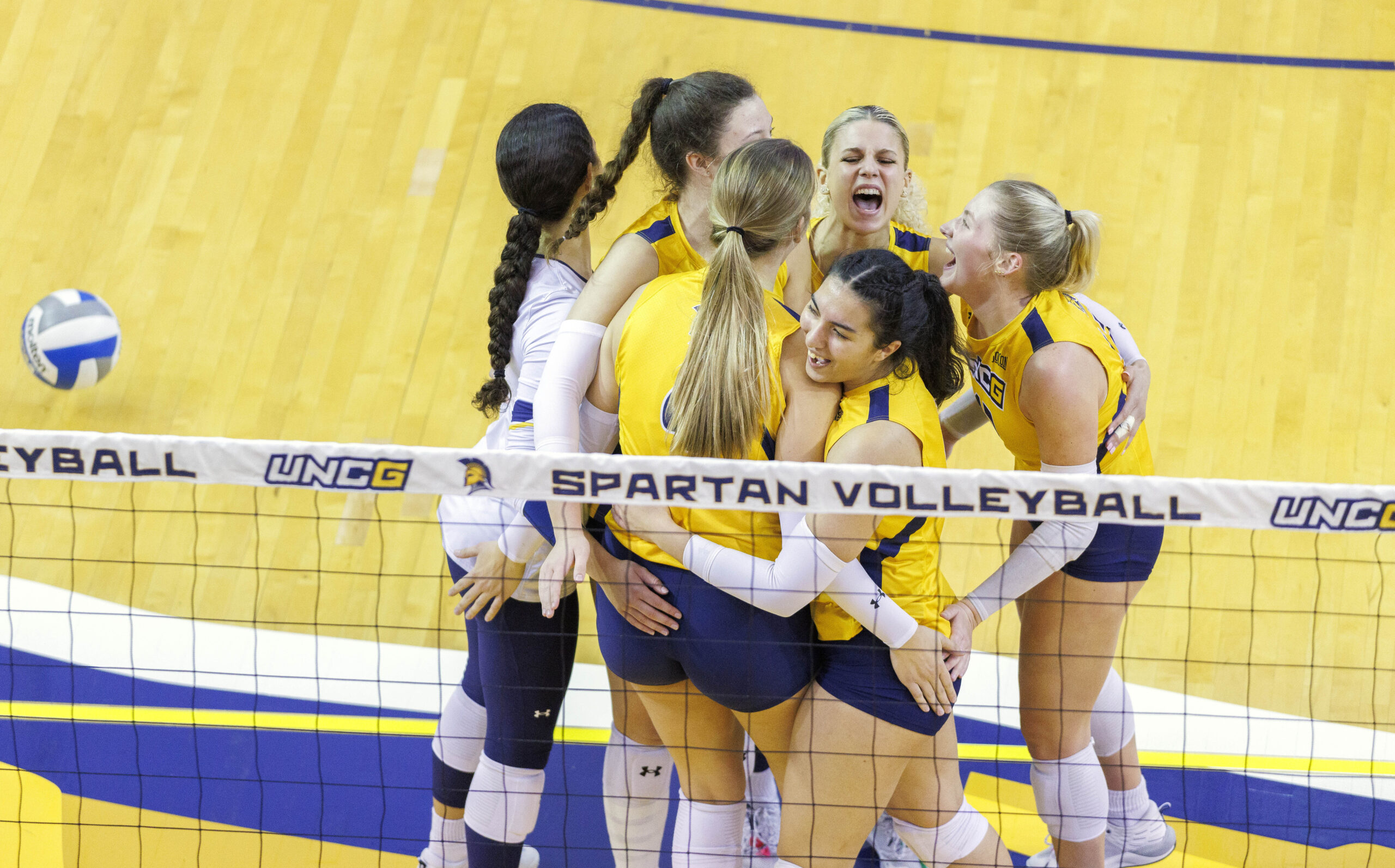 Volleyball team celebrating a point in Fleming Gym.