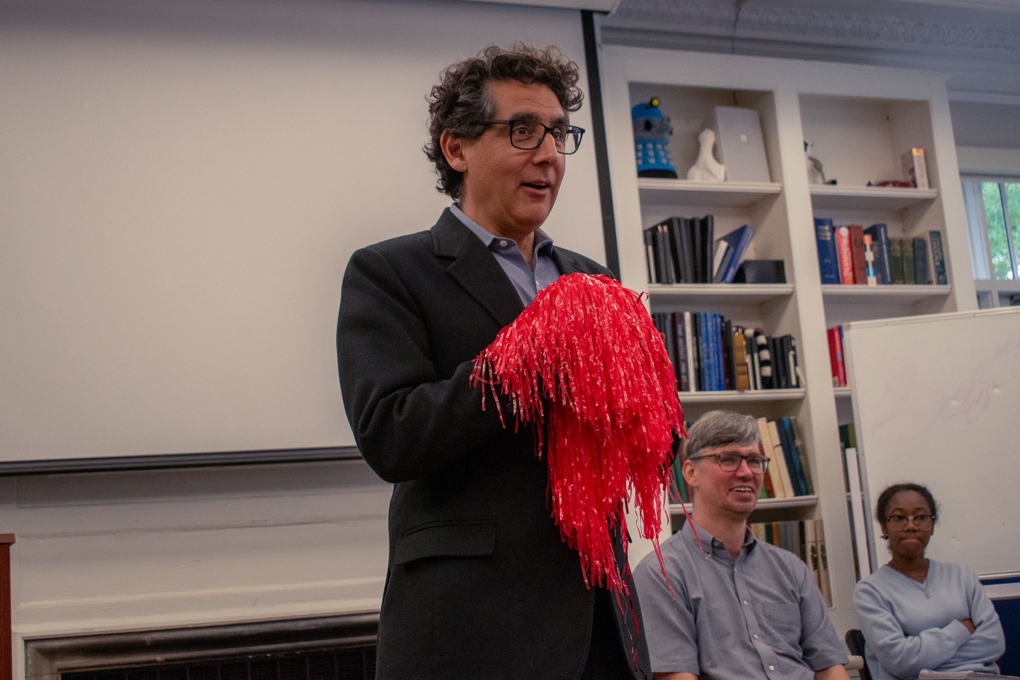 Professor using play as a learning tool, The professor is holding red streamers while speaking.