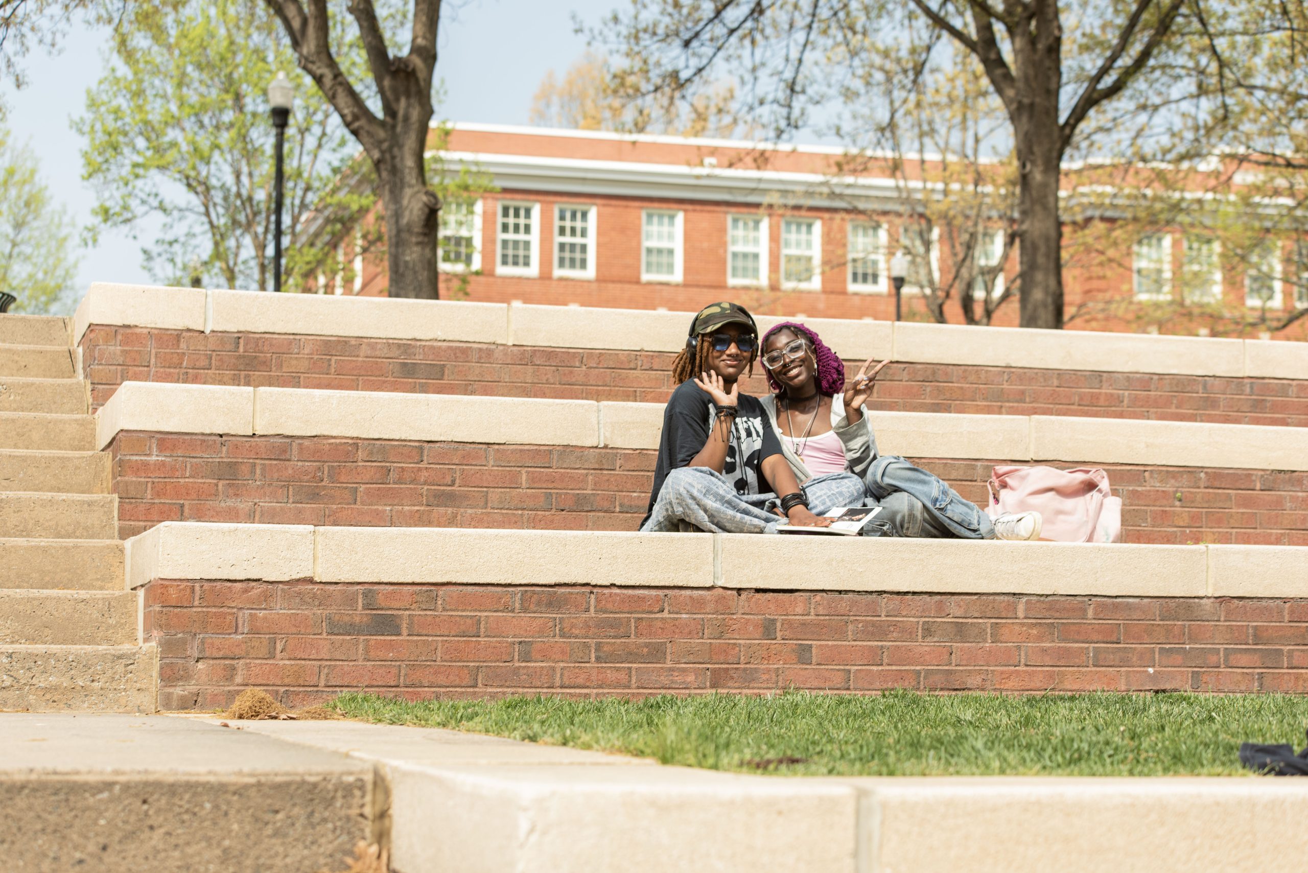 Two girls hang out and pose for the camera on the steps outside of Moran Commons.