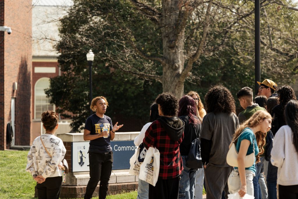 A UNCG student speaks to prospective students and their families on a tour of campus.
