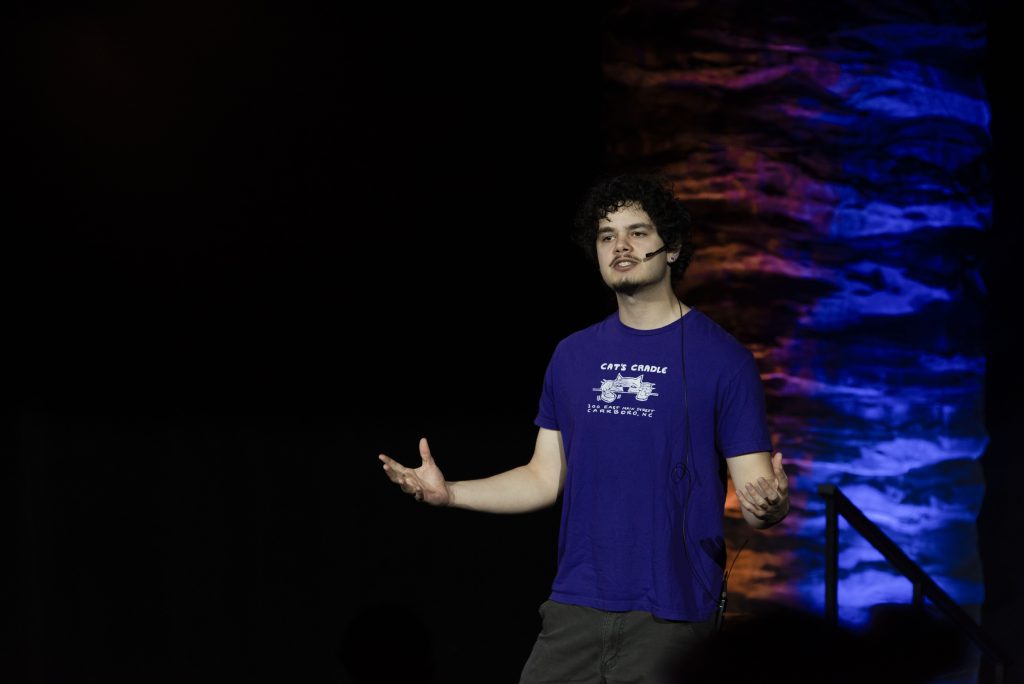A student on a stage speaks in a mic to an audience.