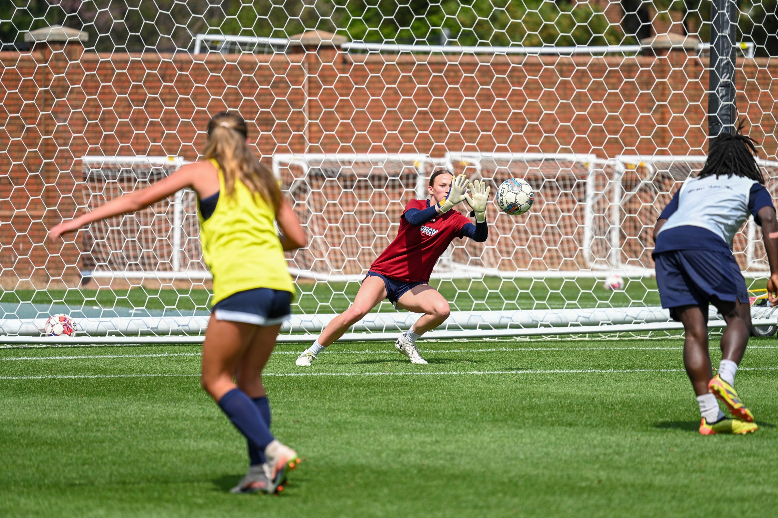 Women's soccer goalkeeper makes a save during practice at UNCG Soccer Stadium.