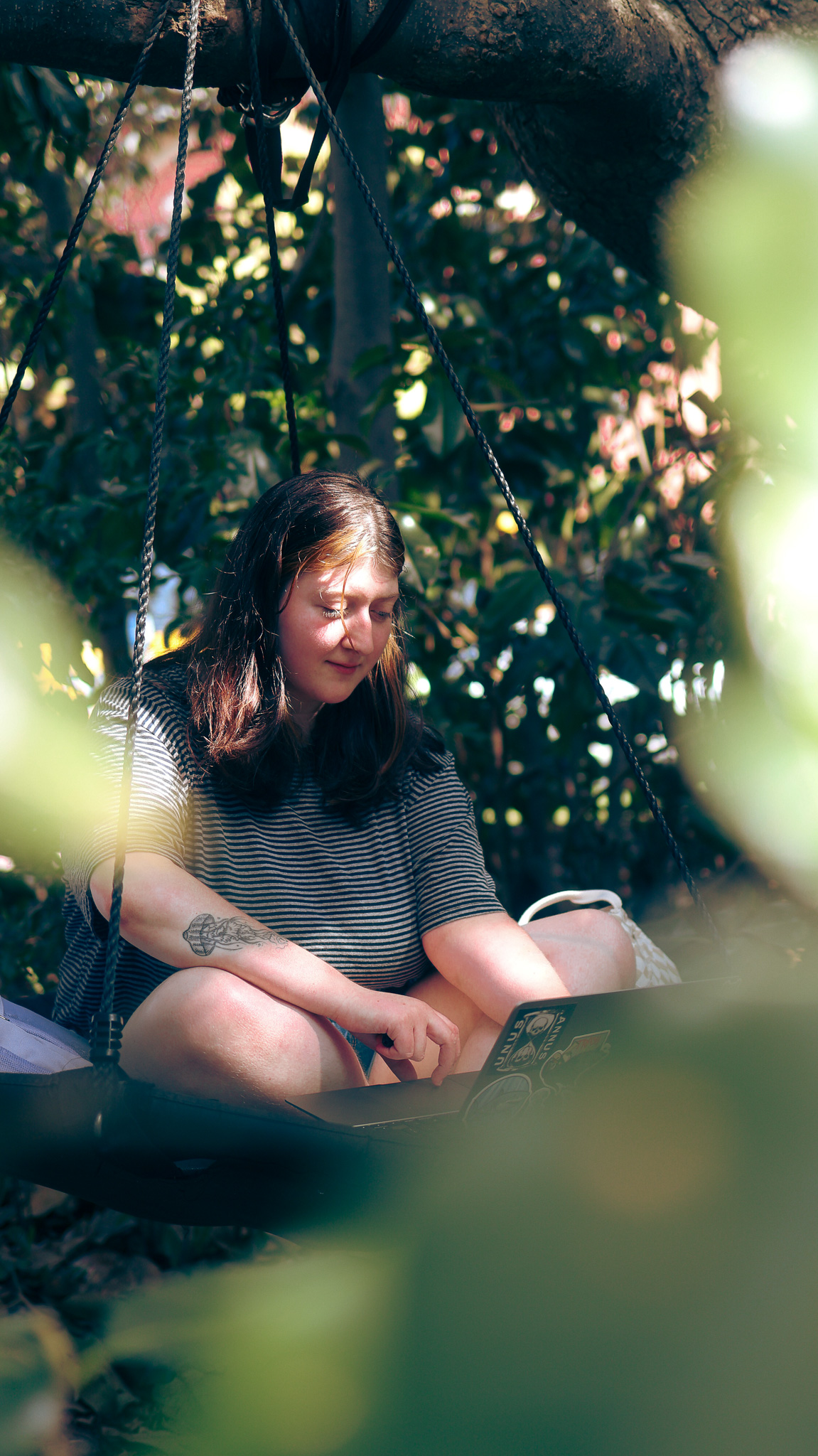 Student studying on a tree swing located in Foust Park.