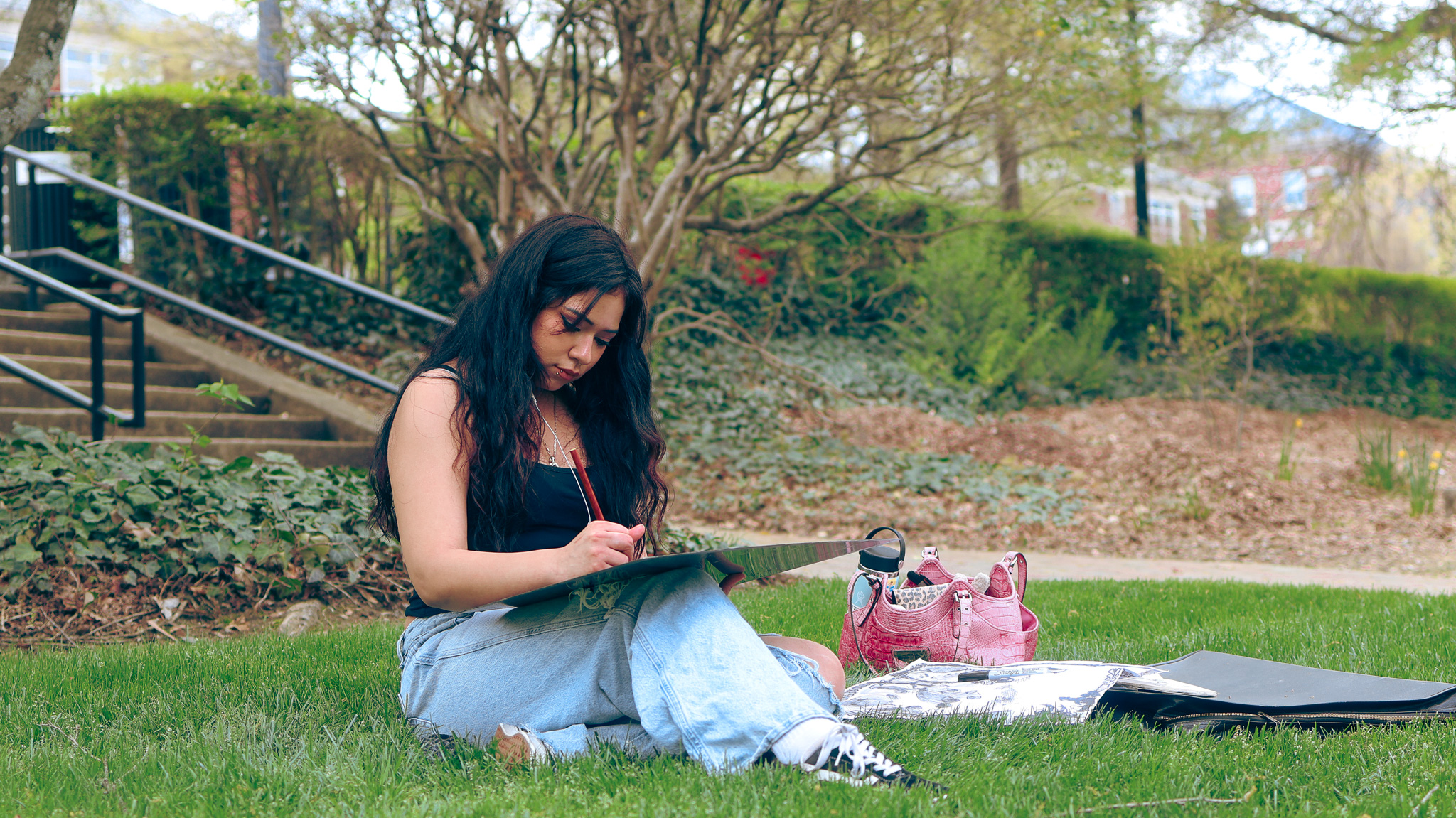 Student taking advantage a warm Friday afternoon to relax and create some art work.