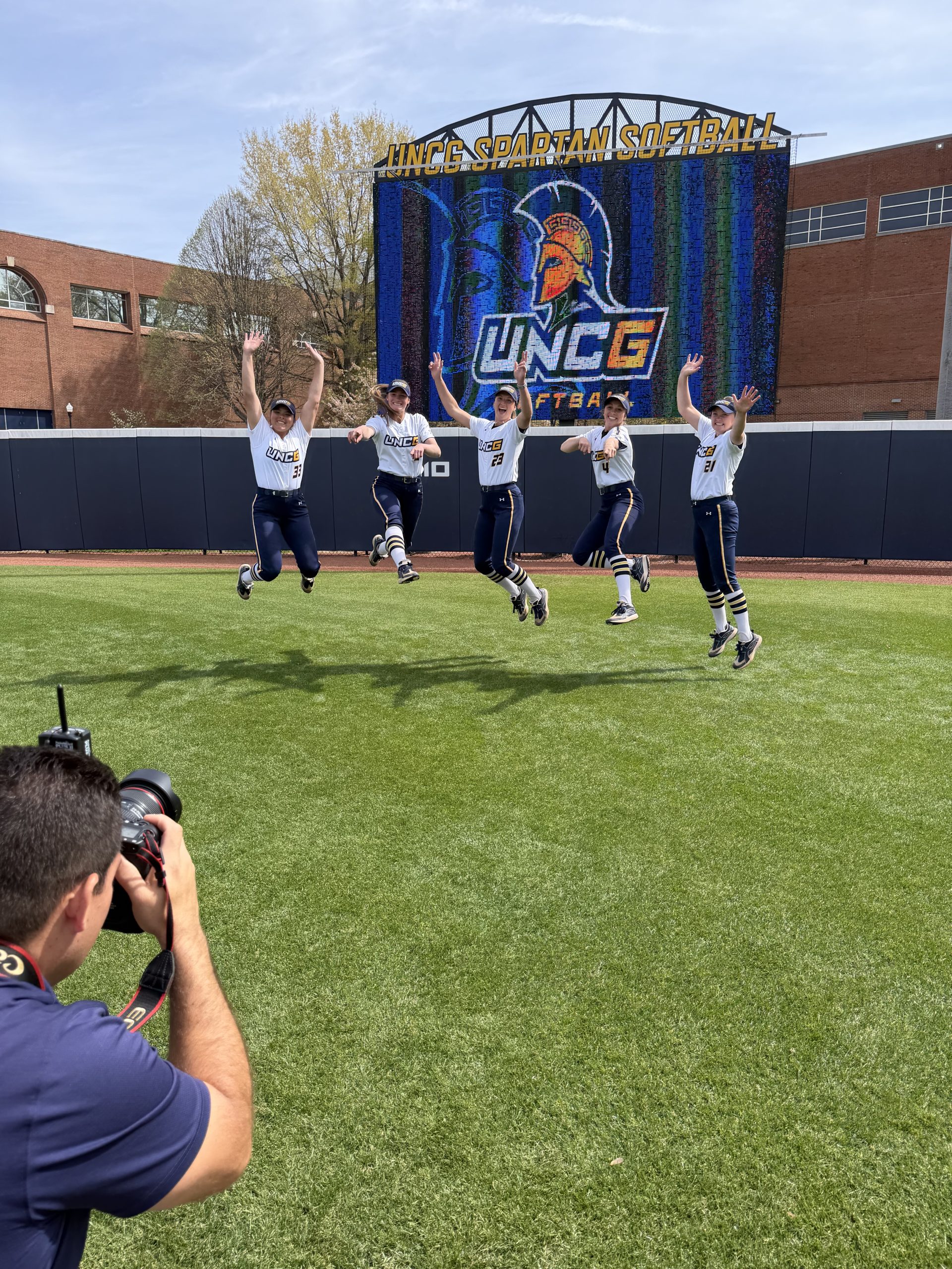 Senior softball student-athletes jump for a picture.