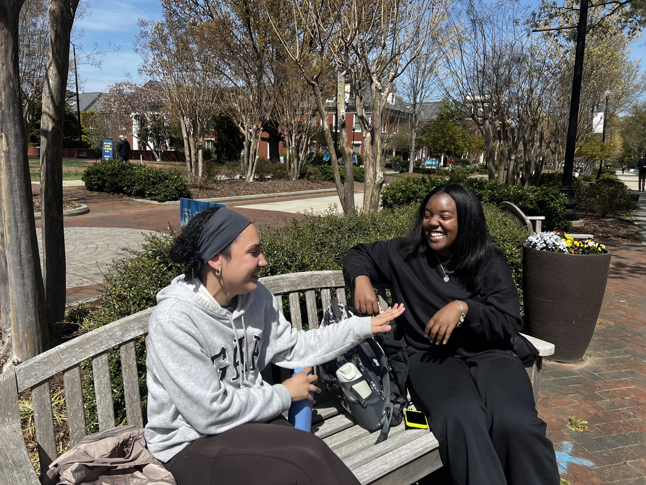Two students engaged in a humorous conversation outside by the Minerva Statue.