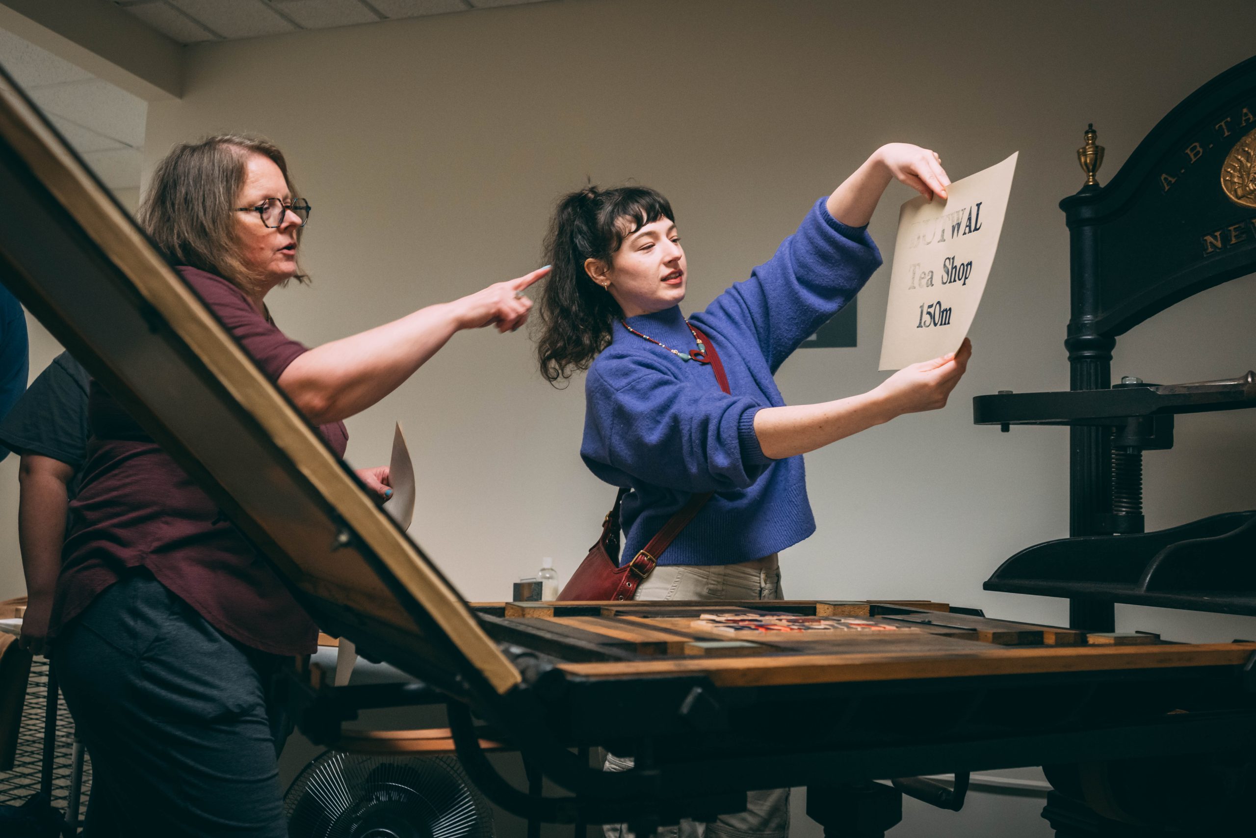 UNCG students learn how to use a printmaking press from the 19th century at the University Archives in Jackson Library.