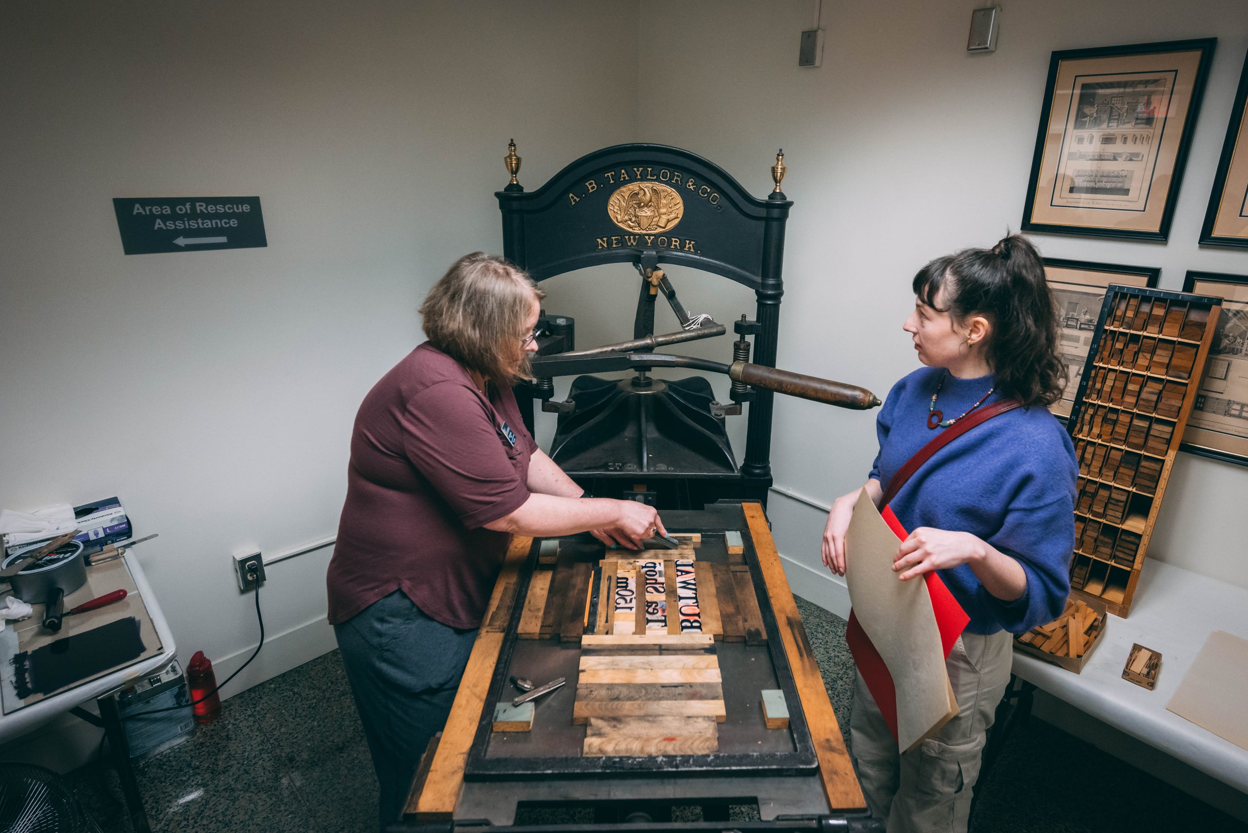 UNCG students learn how to use a printmaking press from the 19th century at the University Archives in Jackson Library.