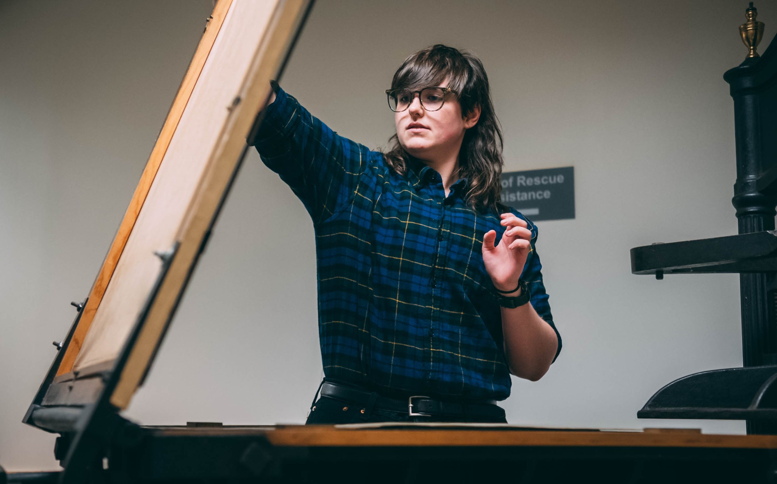 A UNCG student uses a printmaking press from the 19th century at Special Collections and University Archives in Jackson Library.