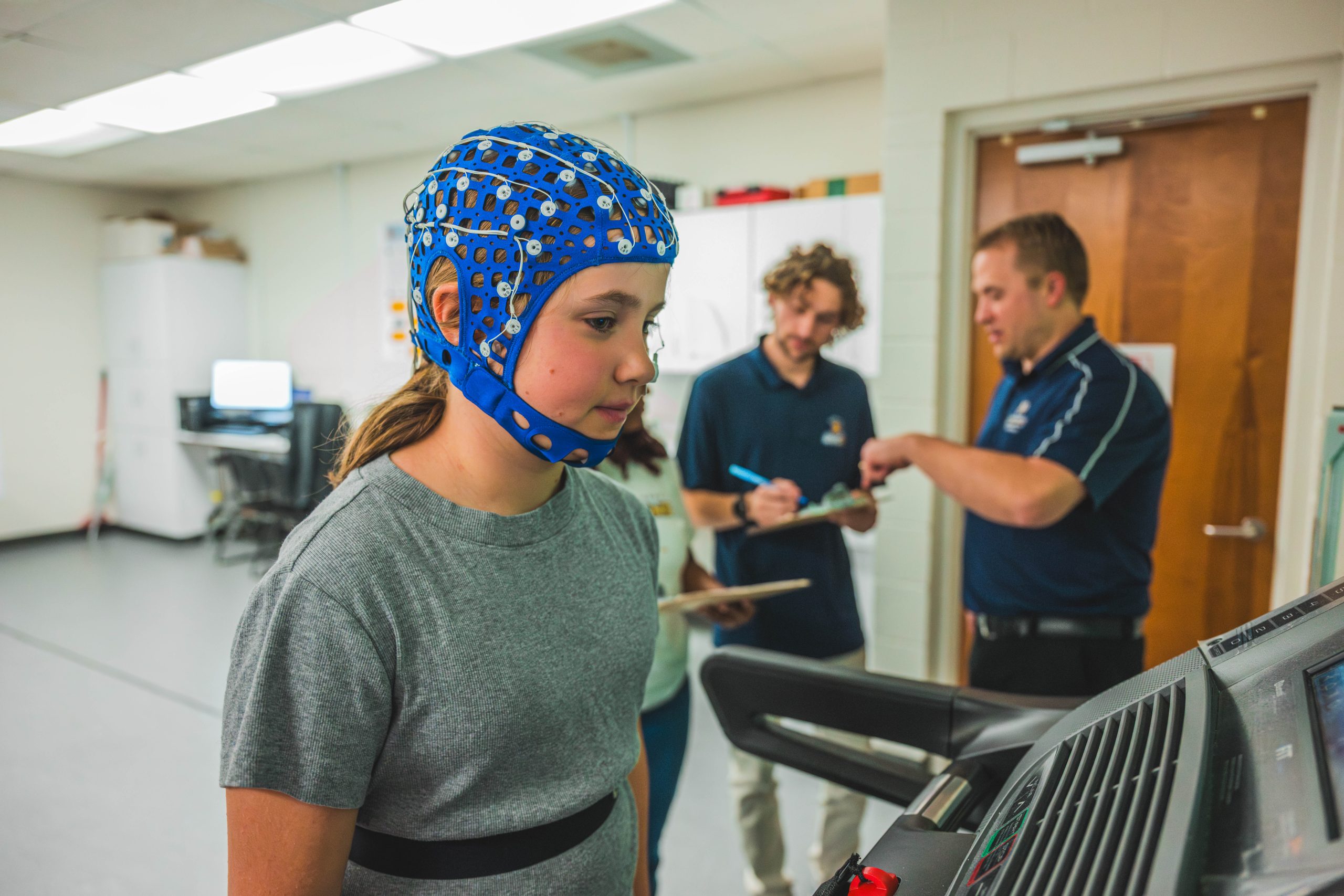 Dr. Eric Drollette's daughter is a good sport about wearing the headgear and measuring how her mind reacts to bursts of exercise.