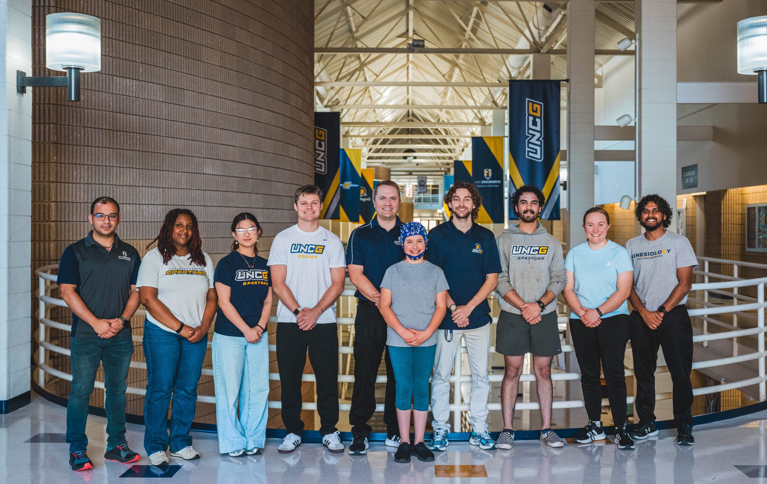 Dr. Eric Drollette, winner of the 2026 Thomas Undergrad Research Mentor Award in the tenure-track category, conducts research in his lab at the Coleman Building with undergraduate and graduate mentees — and one of his girls standing in as the test subject.