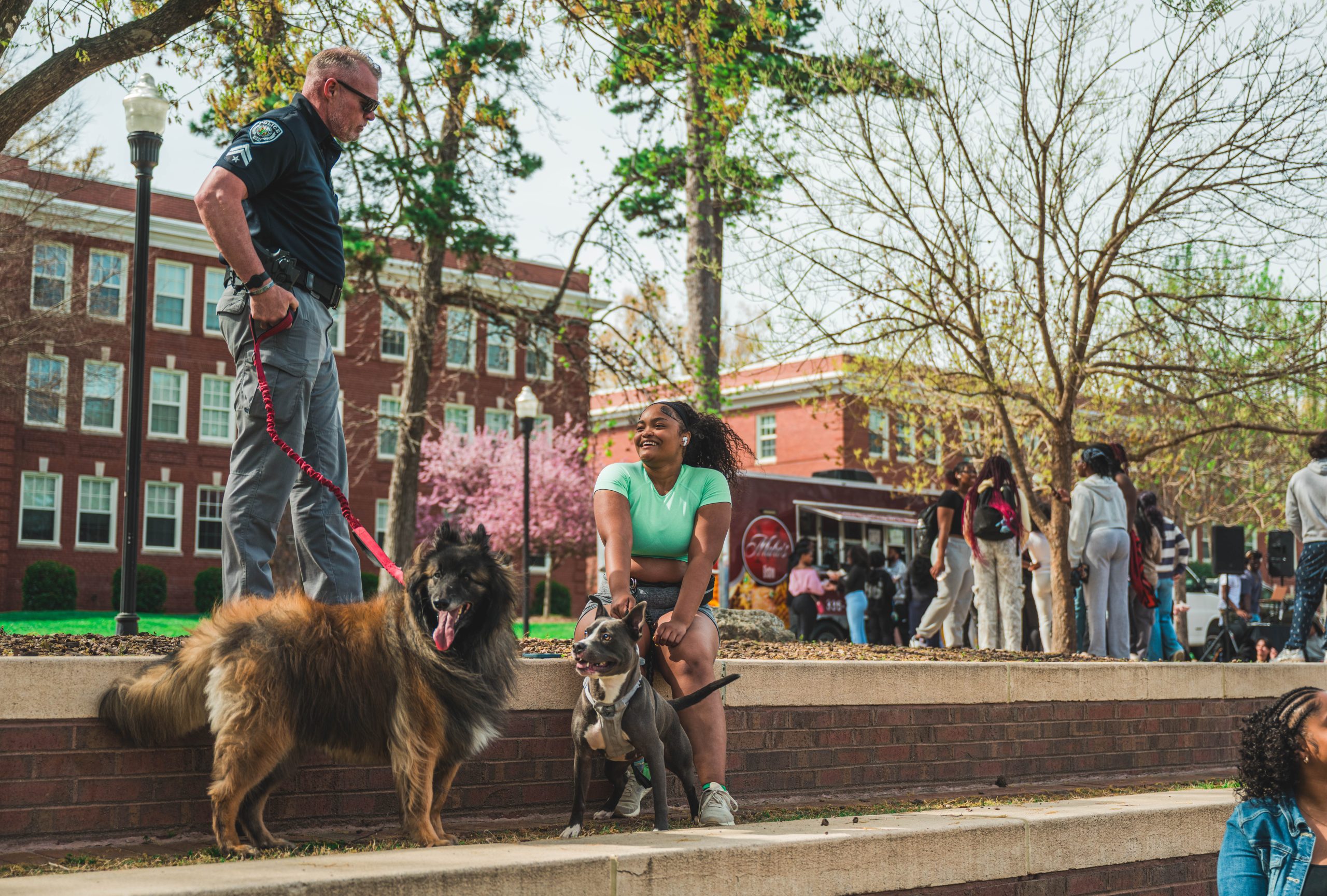 Officer Volser chats with a student at the Fem Fam Fun event at "The Fountain" at Moran Commons as Odin says hello to a fellow pup.
