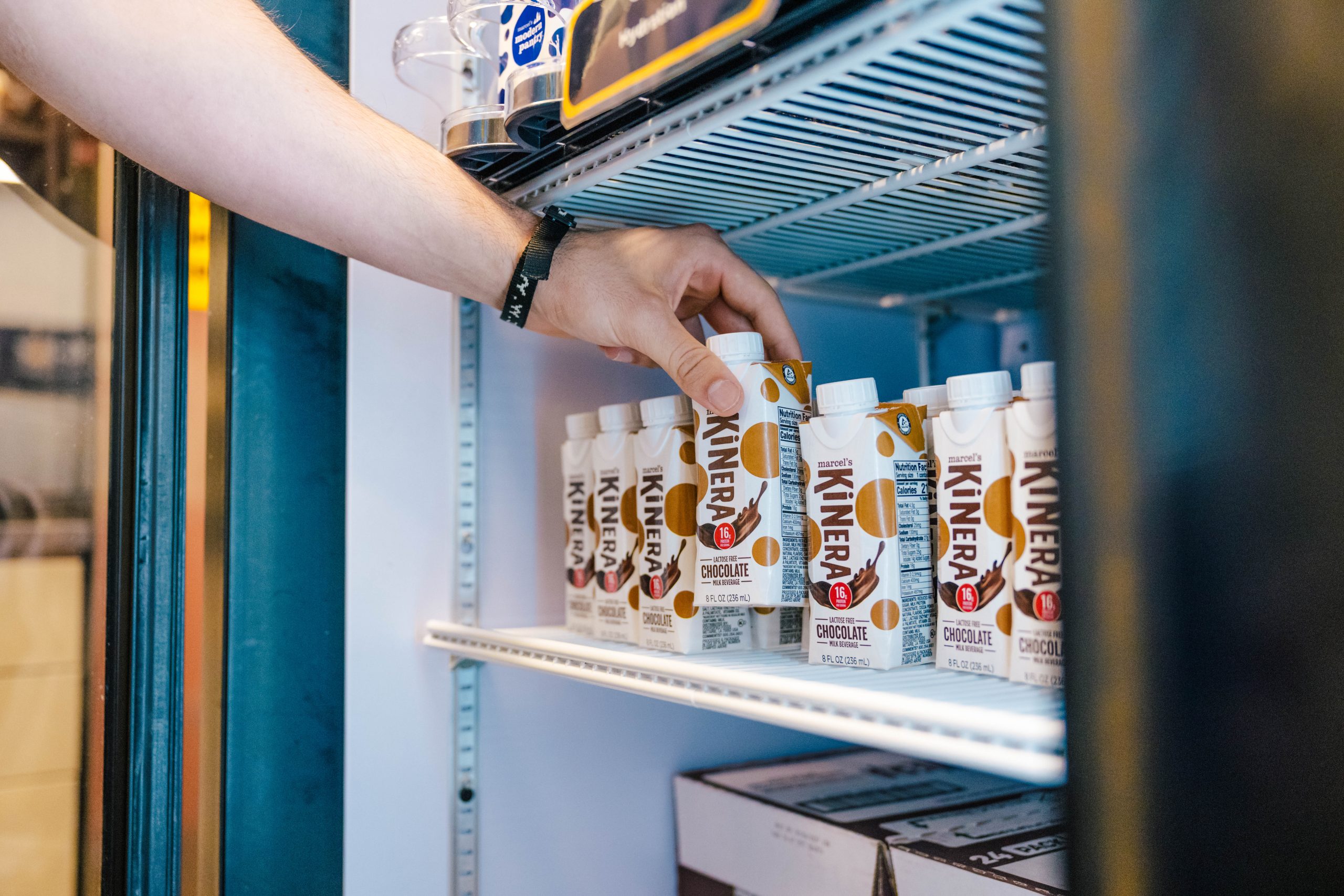 An arm reaches into a fridge for a drink.
