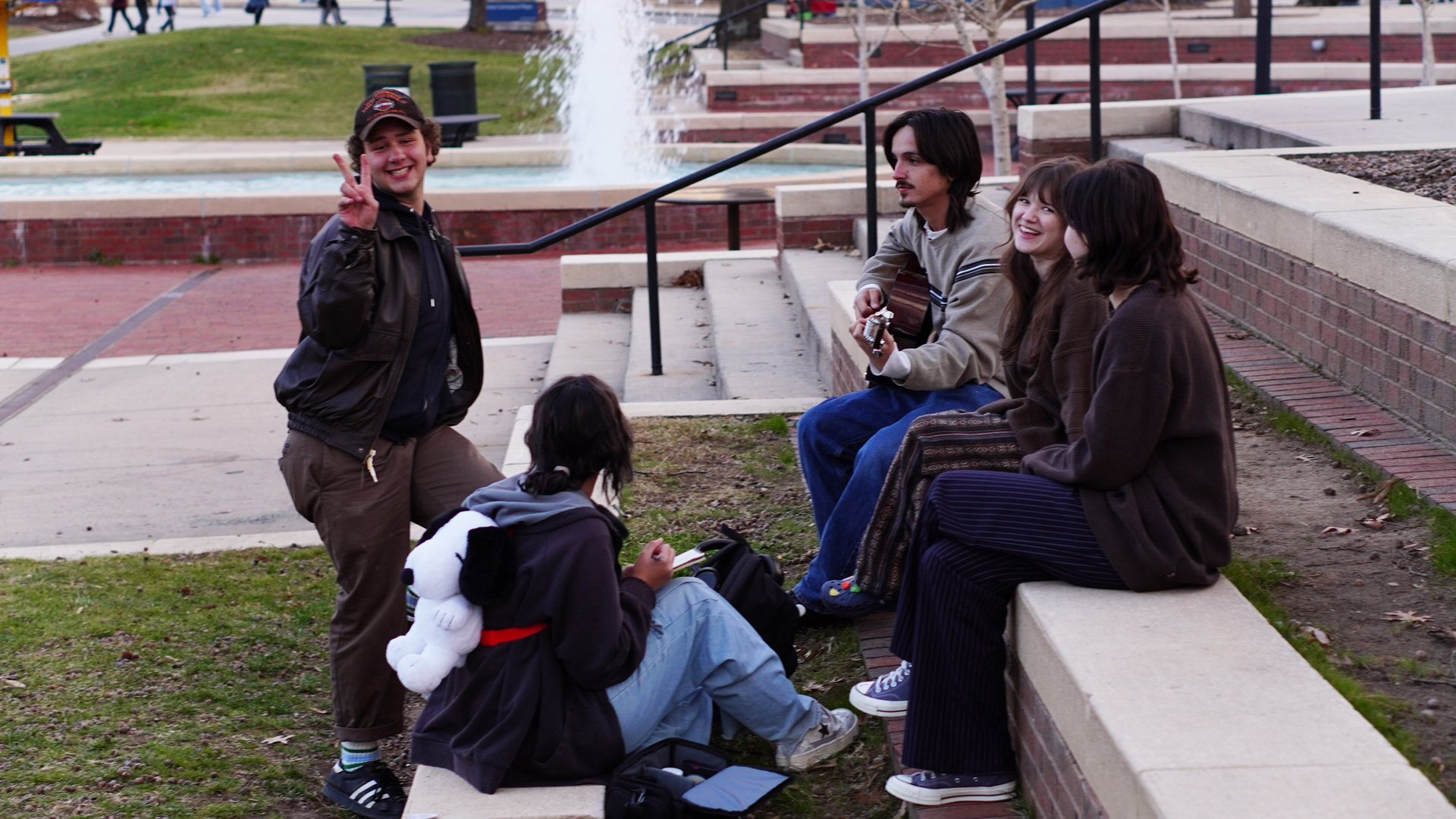 Friends hang out and play music near the Moran Commons fountain.